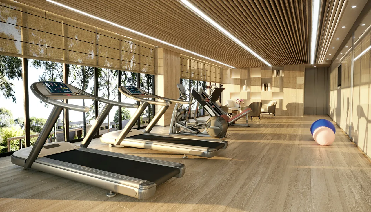Strefa fitness z bieżniami przy dużych oknach